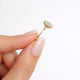 Gold earring with a large diamond held between fingers against a white background