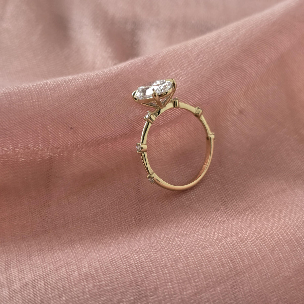 Gold ring with a diamond on a pink fabric background