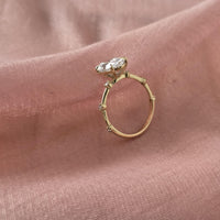 Gold ring with a diamond on a pink fabric background