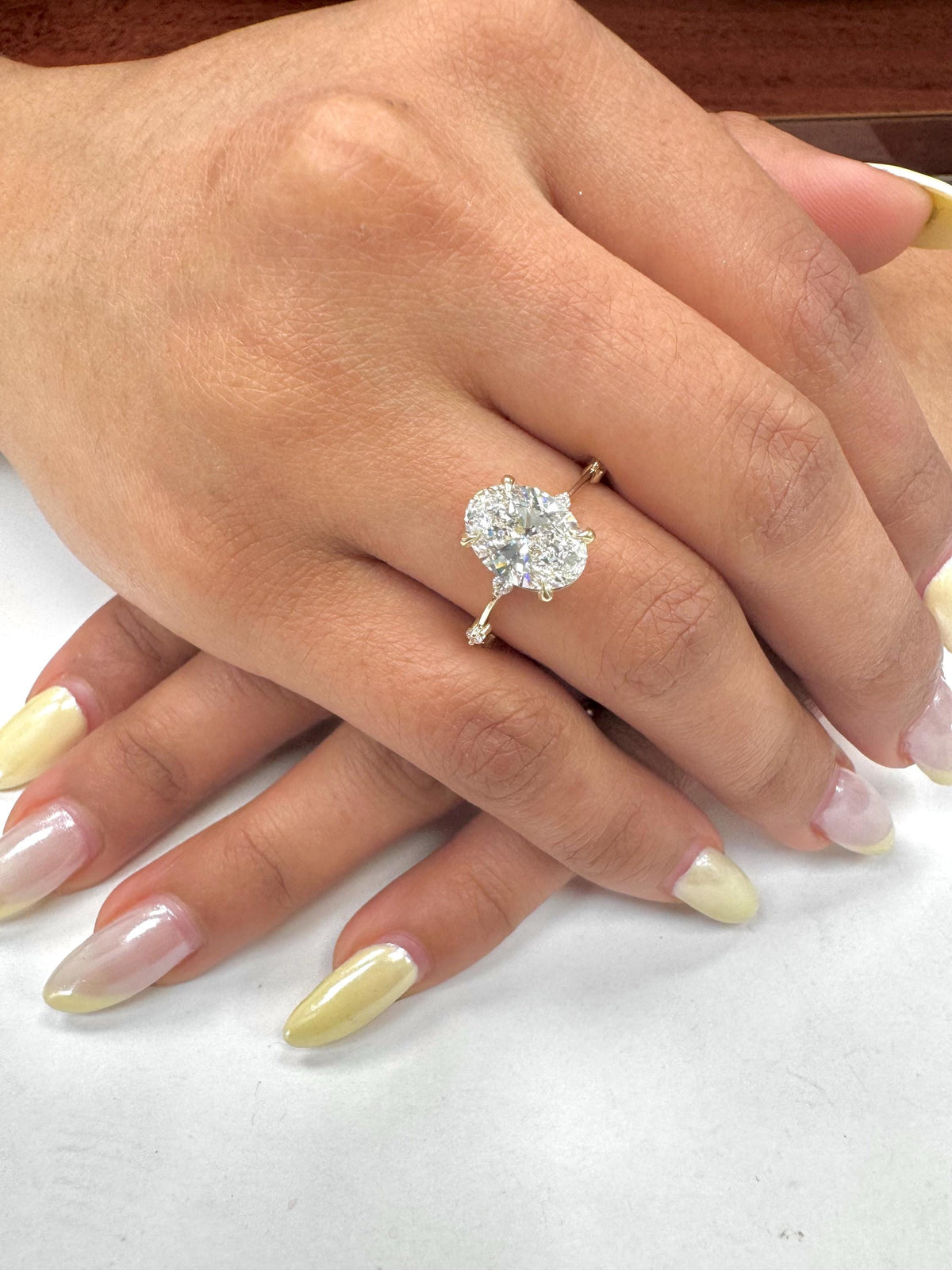 Hand wearing a diamond ring with a light background