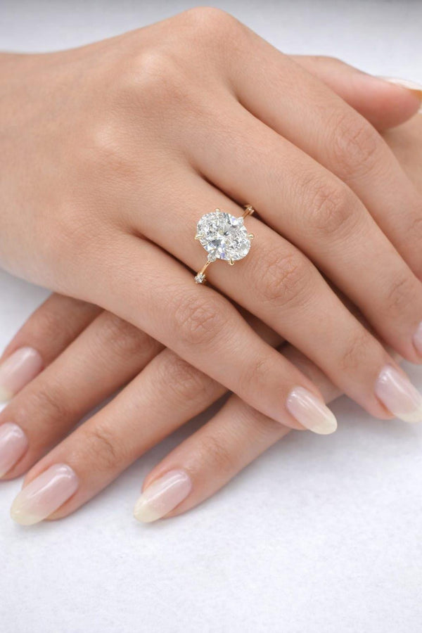 Close-up of a hand wearing a diamond ring on a white background